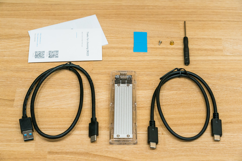 ORICO USB3.1 NVMe M.2 SSDケースと付属品。左上から説明書、熱伝導シート、固定用ネジ、＋ドライバー、USB Type-AtoCケーブル、ケース本体、USB Type-Cケーブル